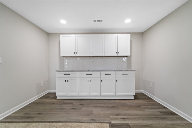 interior space featuring decorative backsplash, white cabinetry, dark hardwood / wood-style floors, and light stone countertops