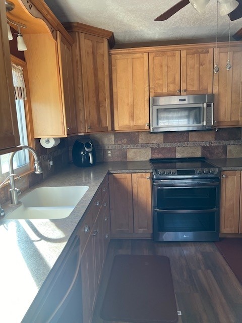 kitchen featuring ceiling fan, sink, stainless steel appliances, dark wood-type flooring, and a textured ceiling