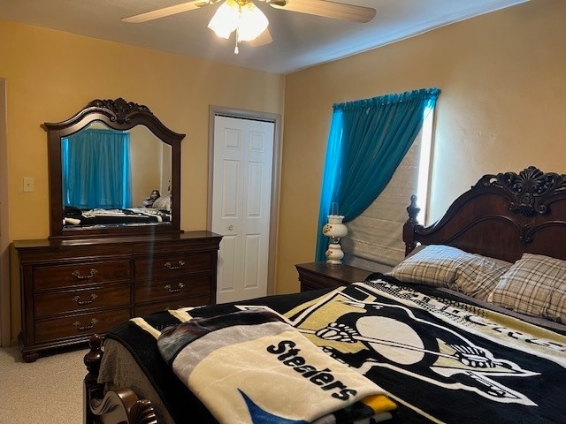 carpeted bedroom with ceiling fan and a closet