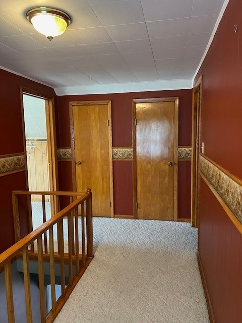 hallway featuring ornamental molding and light colored carpet