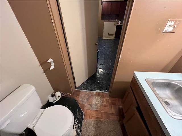 bathroom featuring vanity, toilet, and parquet floors