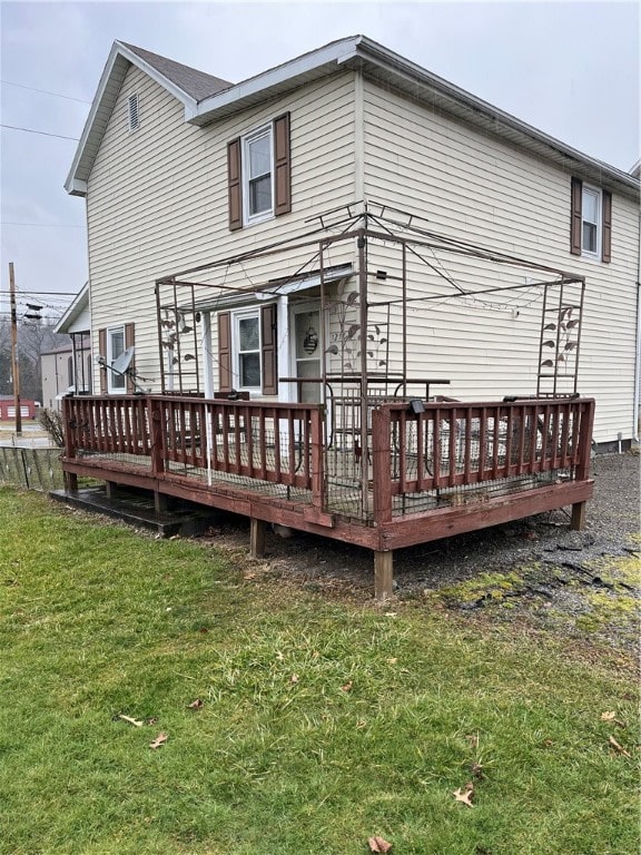 rear view of property featuring a wooden deck and a yard