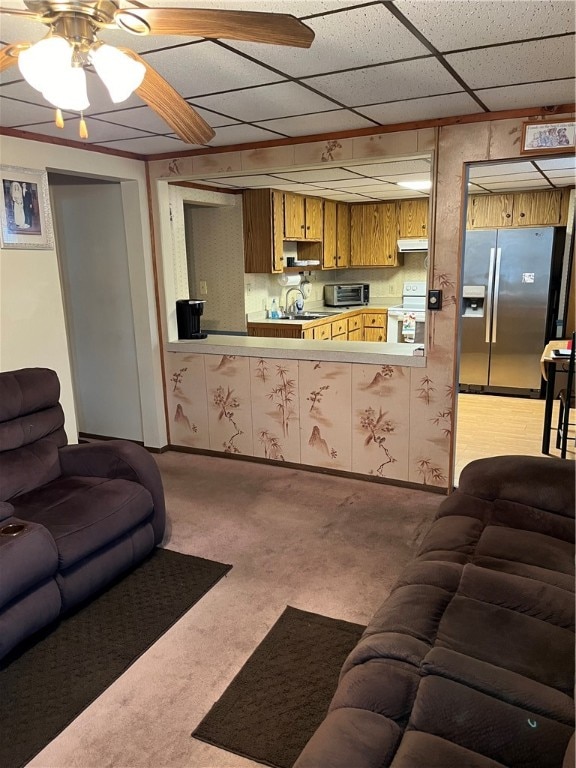 living room featuring carpet floors, ceiling fan, and a drop ceiling