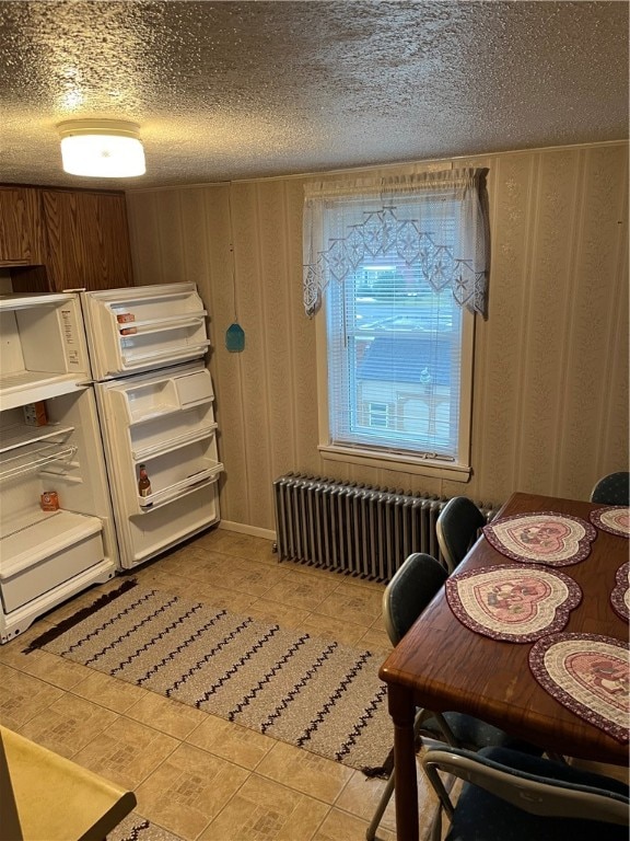 kitchen with a textured ceiling, radiator, and light tile floors