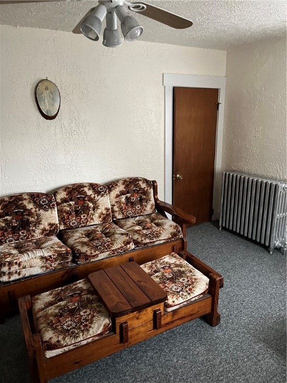 carpeted living room with ceiling fan, a textured ceiling, and radiator heating unit