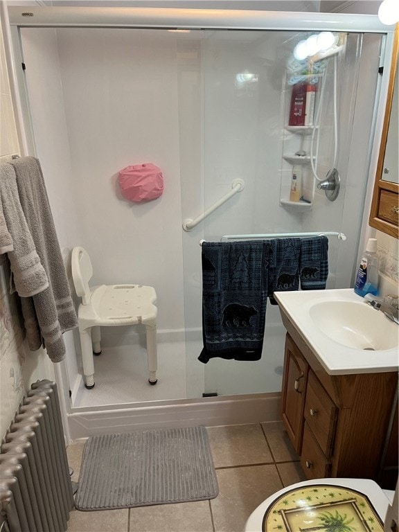 bathroom with radiator heating unit, tile floors, an enclosed shower, and vanity