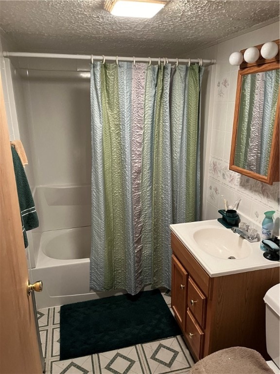 full bathroom featuring oversized vanity, toilet, a textured ceiling, shower / bathtub combination with curtain, and tile floors