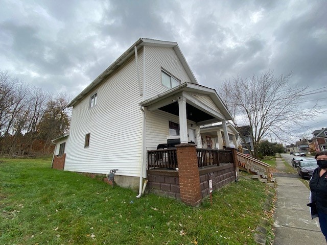 view of property exterior featuring covered porch and a lawn