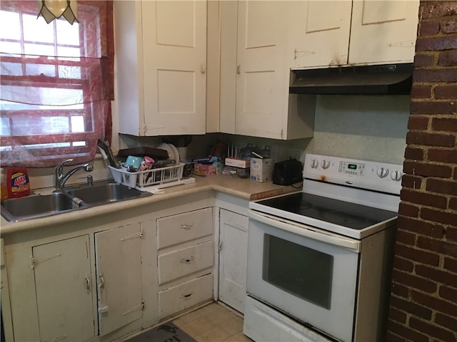 kitchen featuring brick wall, sink, white cabinetry, and white electric stove