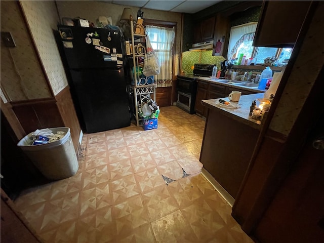 kitchen featuring kitchen peninsula, range hood, sink, black appliances, and dark brown cabinetry