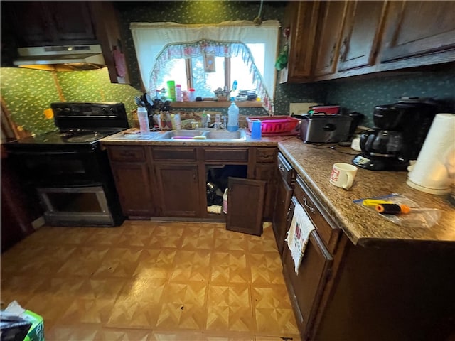 kitchen featuring black electric range oven, sink, dark brown cabinets, and ornate columns