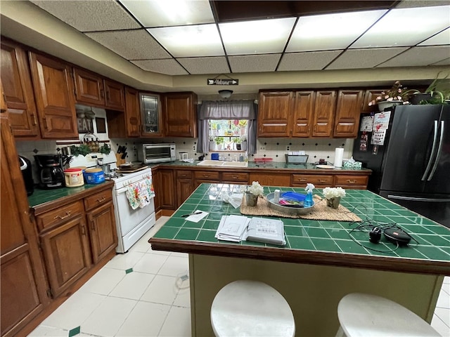 kitchen with a kitchen breakfast bar, white range with gas stovetop, a center island, and black fridge