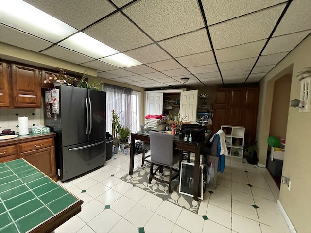 kitchen featuring a drop ceiling and black refrigerator