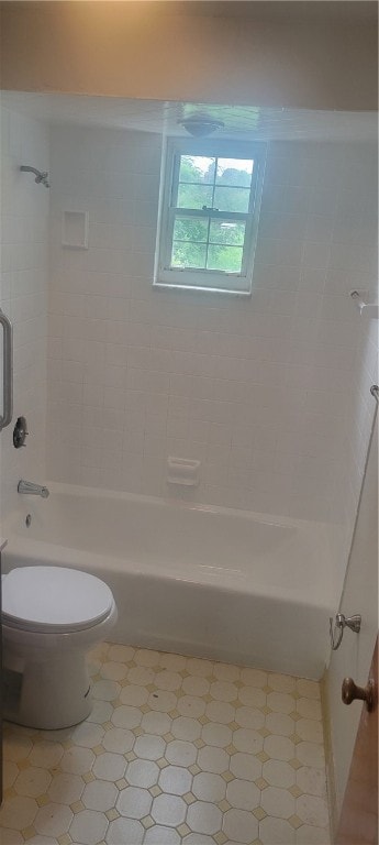 bathroom with tile floors, toilet, and tiled shower / bath combo