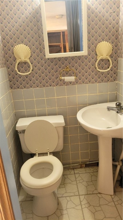 bathroom with toilet, tile flooring, and tile walls