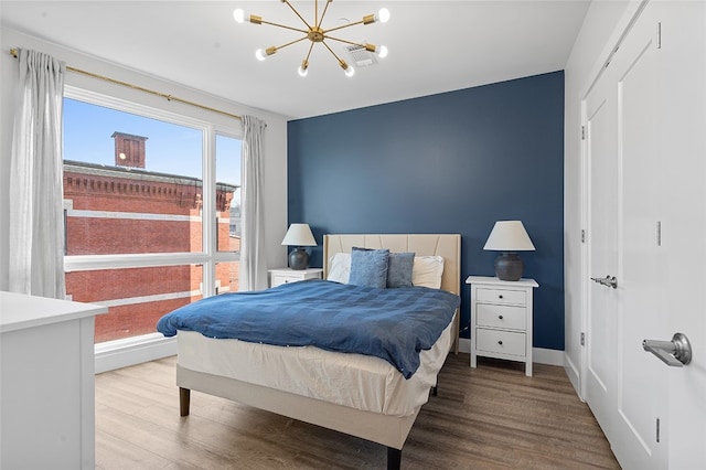 bedroom featuring an inviting chandelier, a closet, and light wood-type flooring