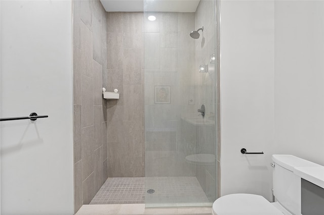 bathroom featuring a shower with door and toilet