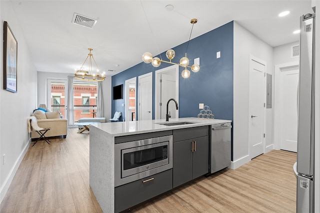 kitchen featuring a notable chandelier, appliances with stainless steel finishes, decorative light fixtures, and light wood-type flooring