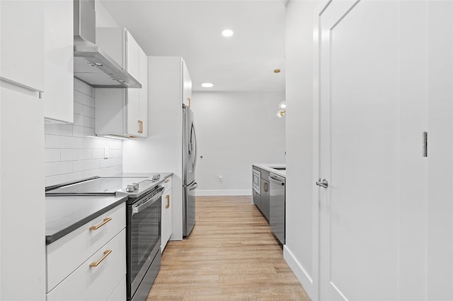 kitchen featuring light hardwood / wood-style flooring, stainless steel appliances, wall chimney range hood, tasteful backsplash, and white cabinetry