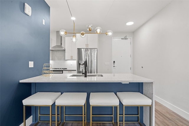 kitchen with white cabinetry, stainless steel fridge, tasteful backsplash, wall chimney exhaust hood, and dark hardwood / wood-style flooring