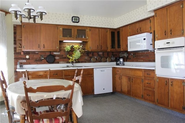 kitchen with an inviting chandelier, sink, white appliances, and decorative light fixtures