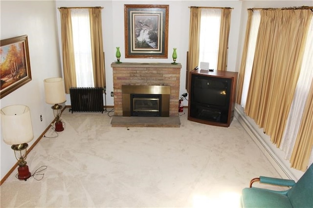 living area with light colored carpet, a wealth of natural light, radiator, and a fireplace