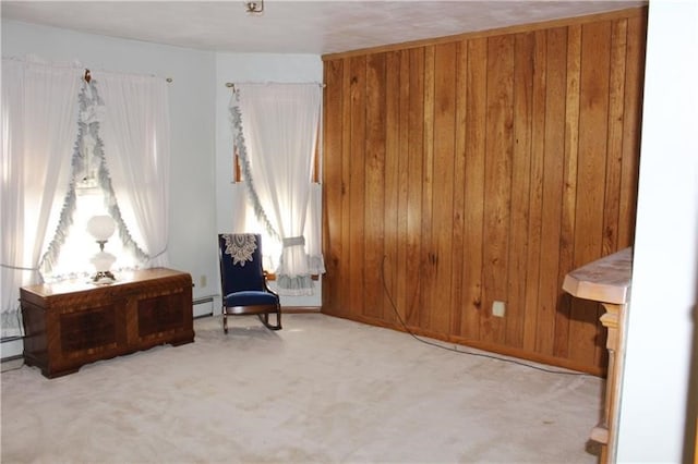 living area with wood walls, light carpet, and a baseboard heating unit