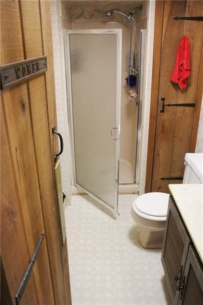 bathroom with tile flooring, toilet, vanity, and a shower with door