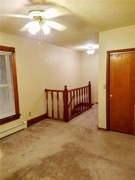 carpeted spare room with ceiling fan, a textured ceiling, and baseboard heating