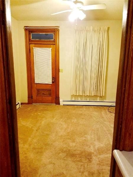 empty room featuring ceiling fan, baseboard heating, and light colored carpet