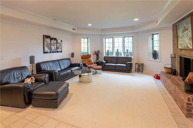 living room with brick wall, ornamental molding, a brick fireplace, and a tray ceiling