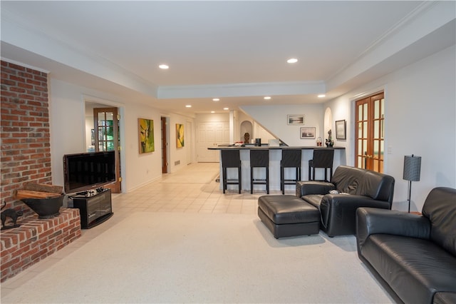 living room with french doors, light colored carpet, ornamental molding, a tray ceiling, and a wealth of natural light