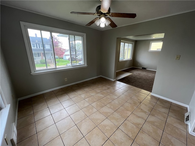 spare room with a wealth of natural light, light tile patterned flooring, and ceiling fan