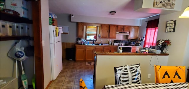 kitchen featuring tile patterned flooring, white refrigerator, range, sink, and kitchen peninsula