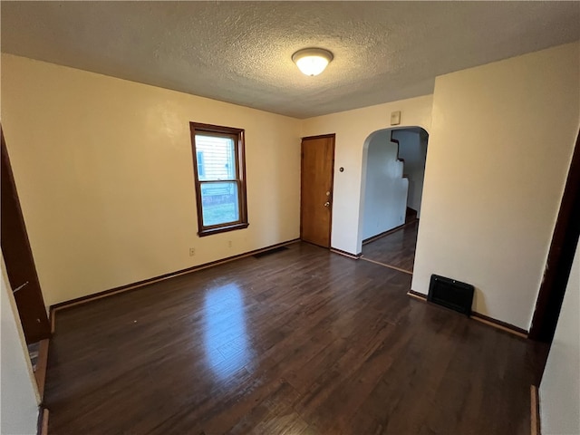 spare room with a textured ceiling and dark hardwood / wood-style floors