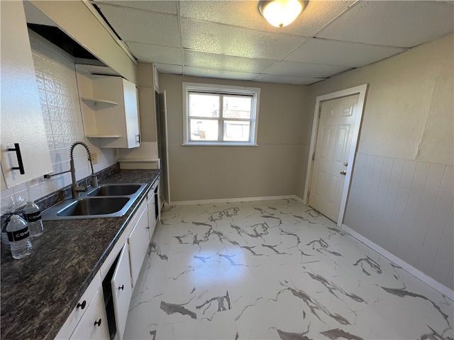 kitchen with sink, a drop ceiling, white cabinets, light tile patterned floors, and dark stone countertops