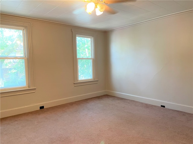 carpeted empty room with ceiling fan, a healthy amount of sunlight, and crown molding