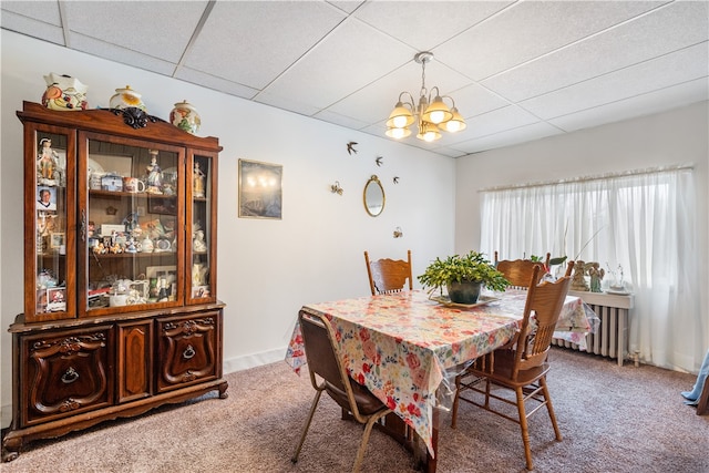 dining area featuring carpet floors, a paneled ceiling, and a notable chandelier