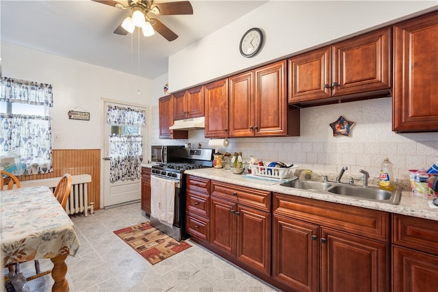 kitchen with light stone counters, ceiling fan, light tile floors, sink, and stainless steel gas range