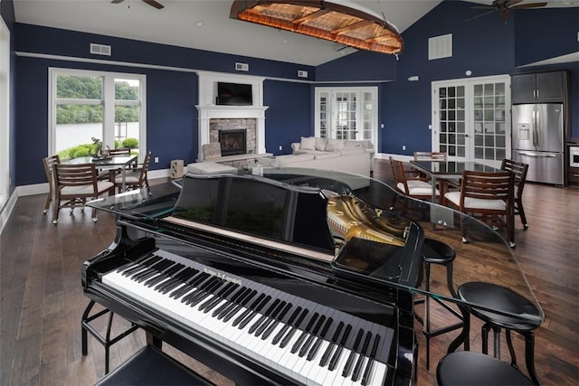 miscellaneous room with lofted ceiling, ceiling fan, a fireplace, dark wood-type flooring, and french doors