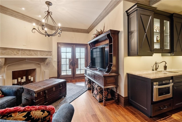 living room featuring sink, ornamental molding, and light hardwood / wood-style floors