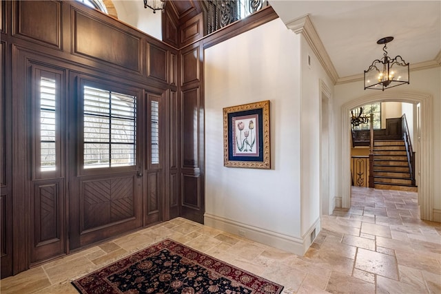 entryway featuring light tile patterned flooring, a notable chandelier, crown molding, and a wealth of natural light