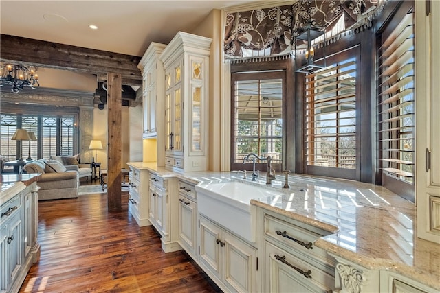 kitchen with dark wood-type flooring, light stone countertops, sink, and an inviting chandelier