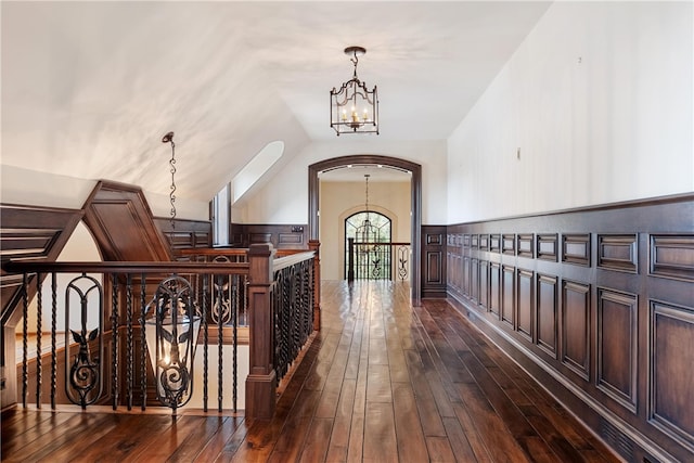 corridor featuring dark wood-type flooring and an inviting chandelier