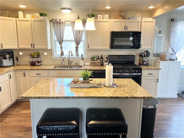 kitchen with a kitchen breakfast bar, range with gas cooktop, light hardwood / wood-style flooring, white cabinets, and light stone counters