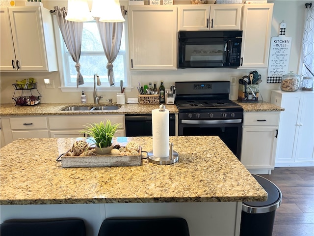 kitchen featuring dark wood-type flooring, a breakfast bar, sink, white cabinetry, and black appliances