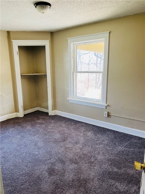 unfurnished bedroom featuring a closet, dark colored carpet, and a textured ceiling