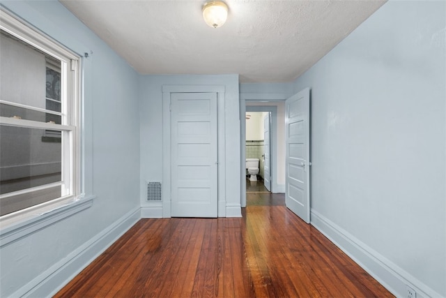 empty room with dark hardwood / wood-style floors and a textured ceiling