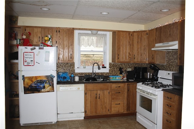 kitchen with white appliances, dark tile floors, sink, a paneled ceiling, and tasteful backsplash