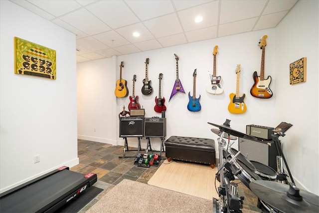 workout area with a drop ceiling and dark tile flooring